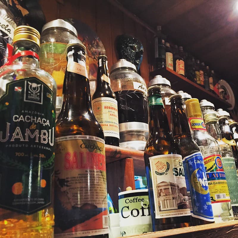 Brazilian cachaça bottles lined up on a wooden bar shelf, traditional sugarcane spirit used in Brazilian cocktails