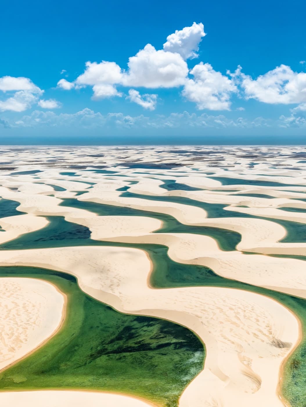 Aerial view of turquoise rain-filled lagoons winding between white sand dunes in Lençóis Maranhenses National Park, Maranhão