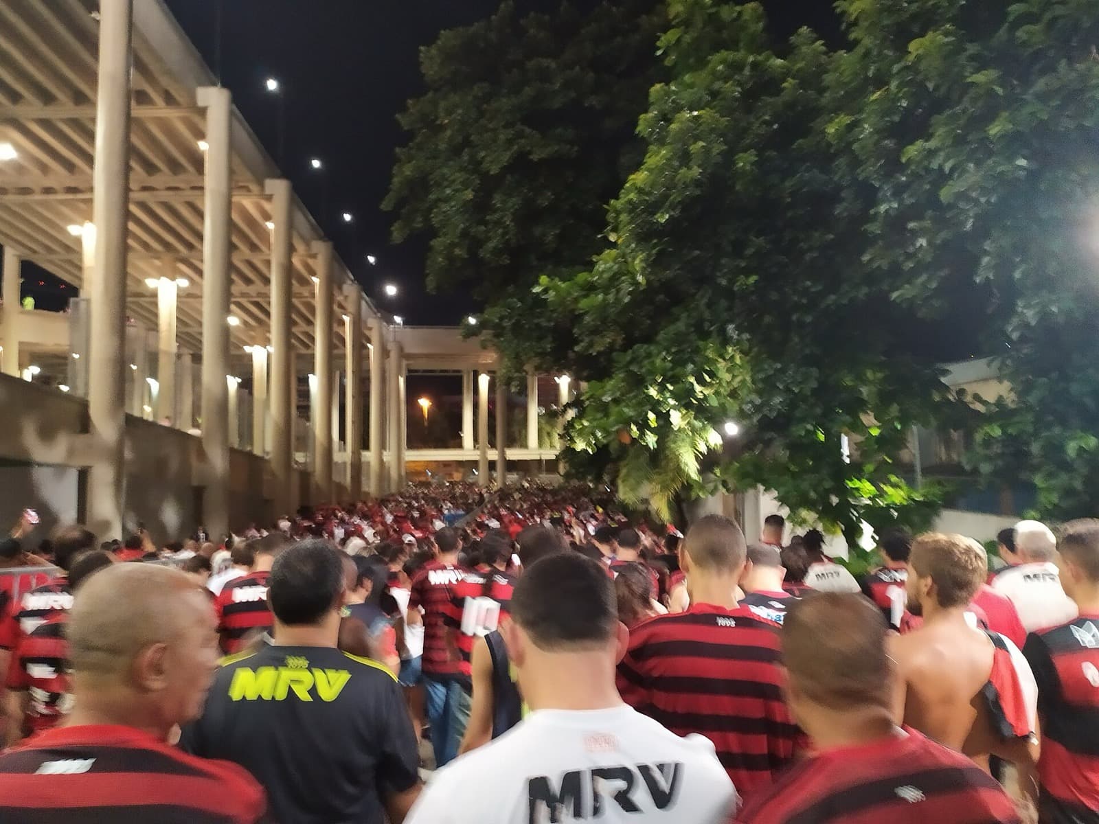 Crowd of Flamengo fans in red and black walking down the Maracanã ramps together after a night match
