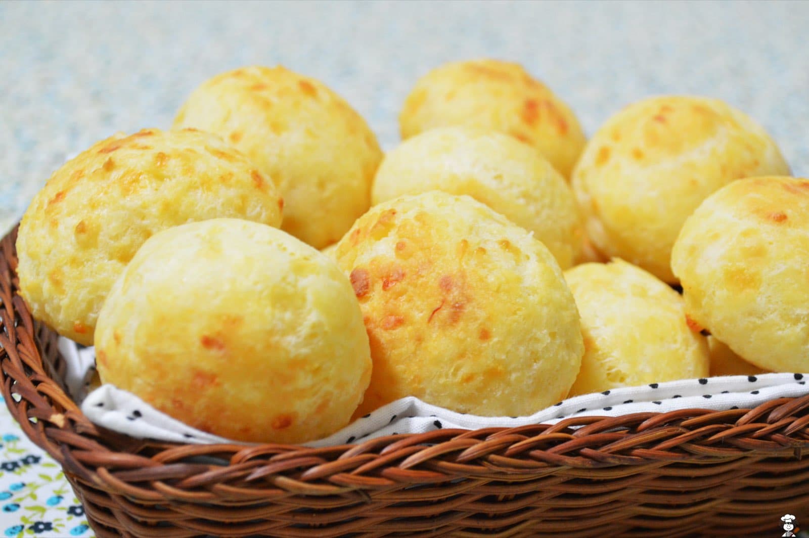 Homemade pão de queijo, Brazilian cheese bread, piled golden in a wicker basket lined with a polka-dot cloth