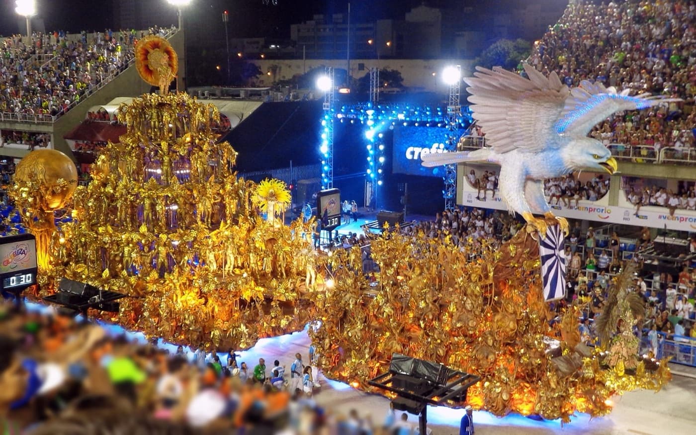 An elaborate golden Portela samba school float topped with a giant eagle, the school's emblem, parading at night in the Sambadrome during Carnival in Rio de Janeiro.