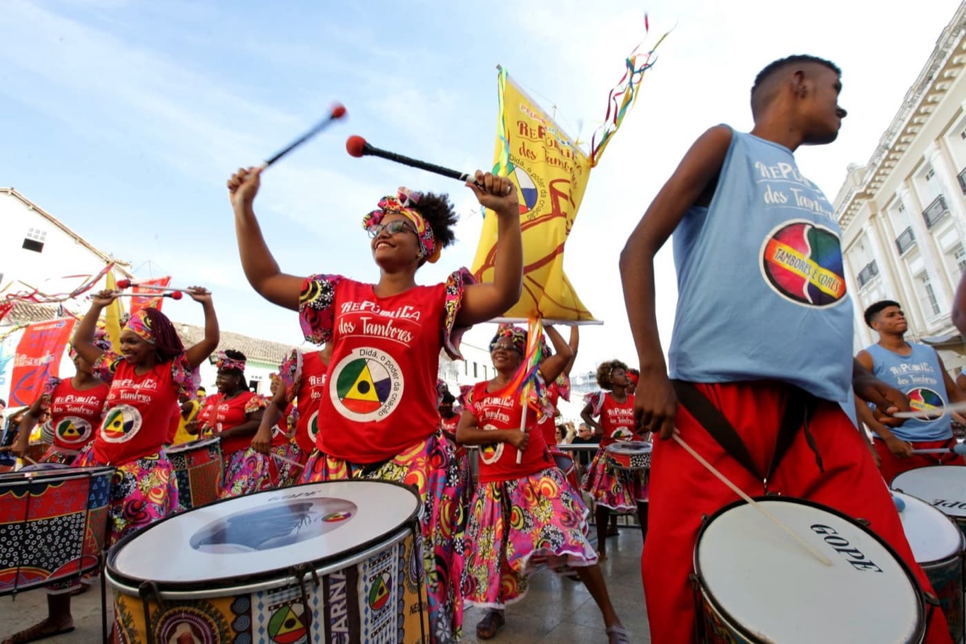 Drummers of the República dos Tambores percussion group in red and blue costumes playing during Salvador's street Carnival.