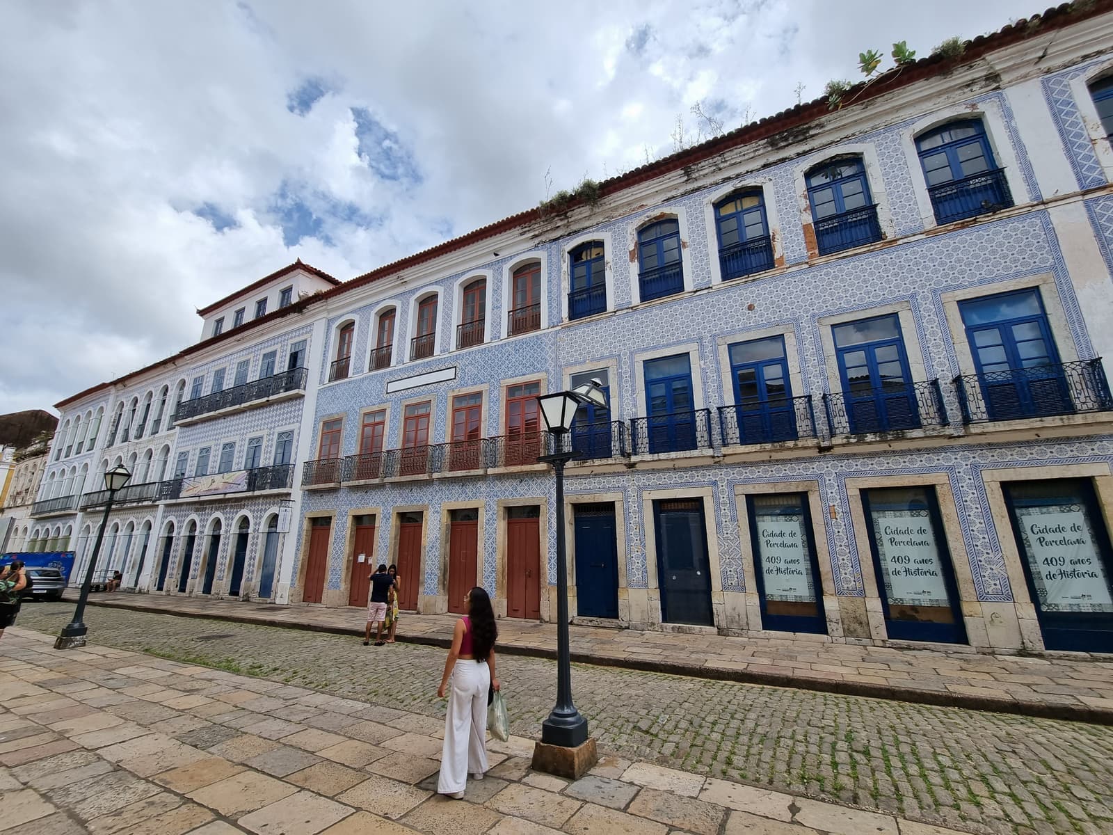 A row of colonial mansions faced in blue-and-white azulejo tiles, with wrought-iron balconies and a cobbled street, in the historic center of São Luís