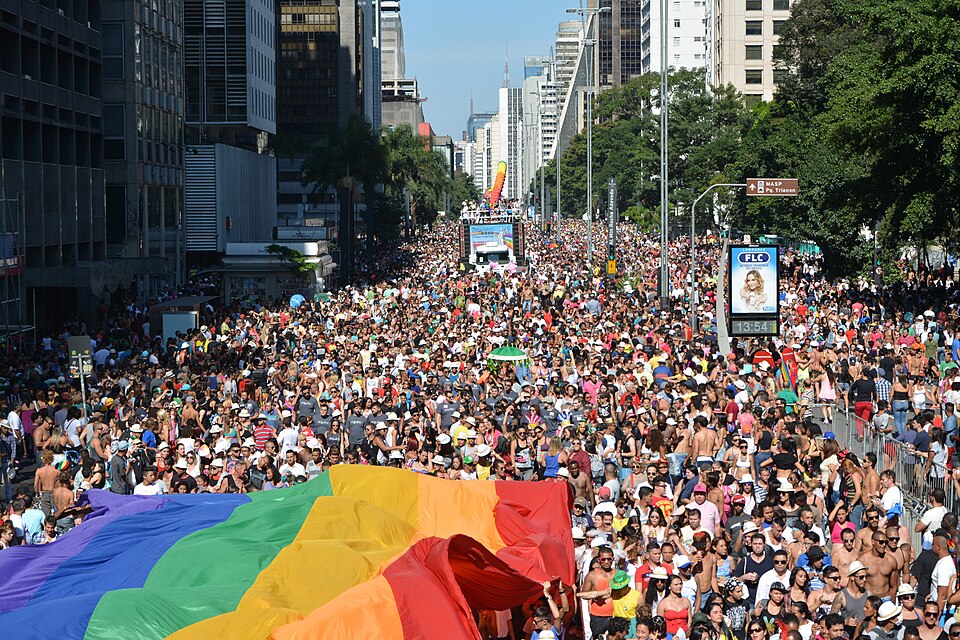 Crowds celebrating with rainbow flags along Avenida Paulista during the São Paulo LGBTQ+ Pride Parade